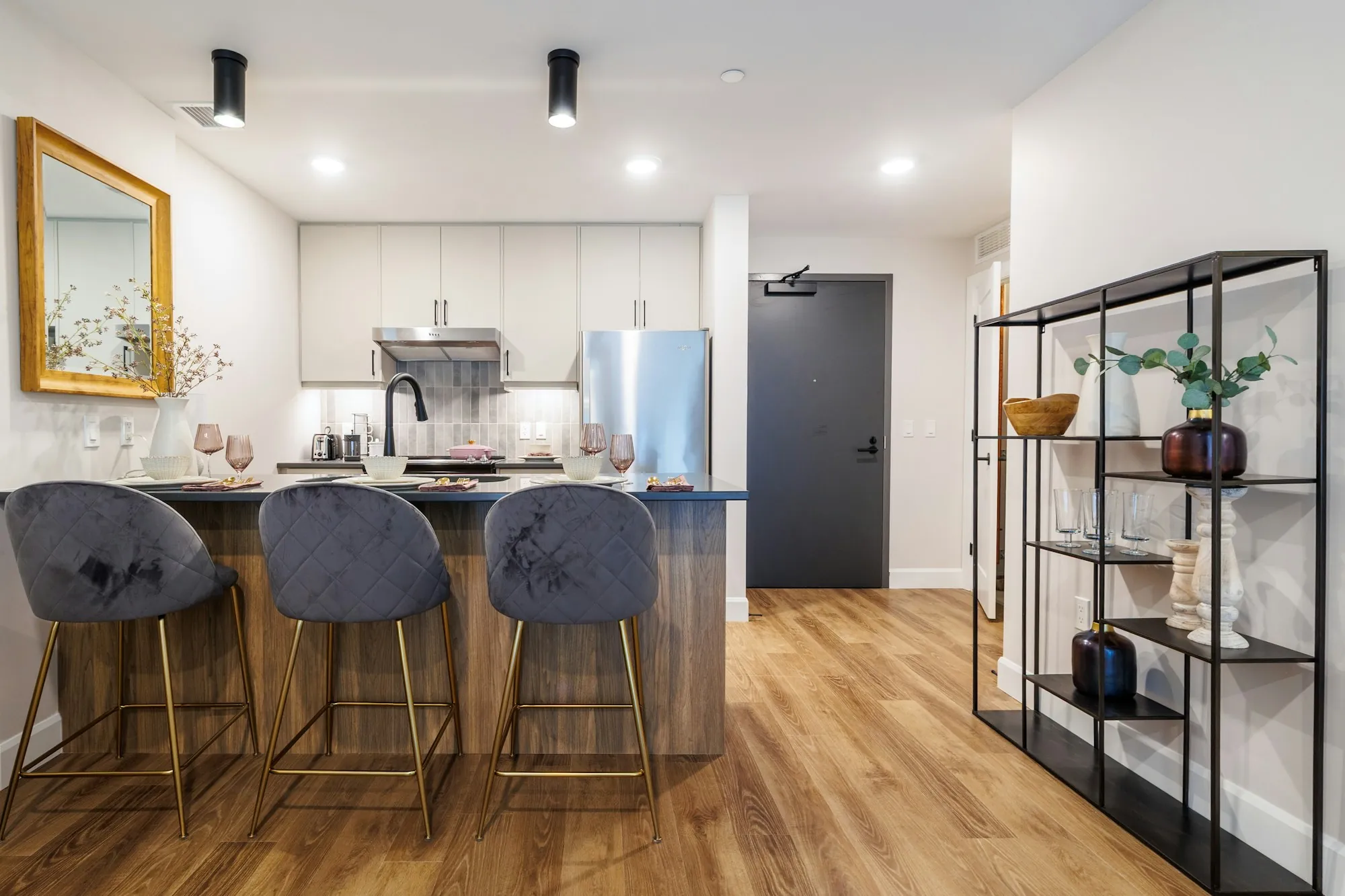 Kitchen with velvet bar stools, open shelving and wood floors